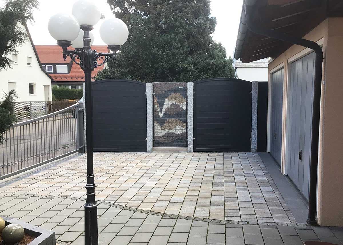 Sichtschutzwand in Anthrazit in Kombination mit einer Steinmauer auf dem Hof in der Einfahrt zum Garten