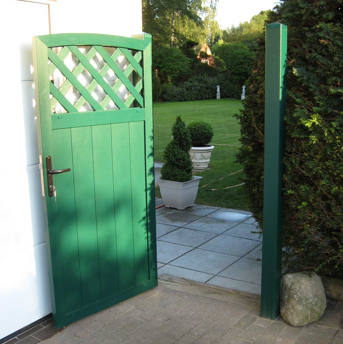 Sichtschutzzaun aus PVC in Grün mit passender Tür für den Zugang zur Gartenterrasse