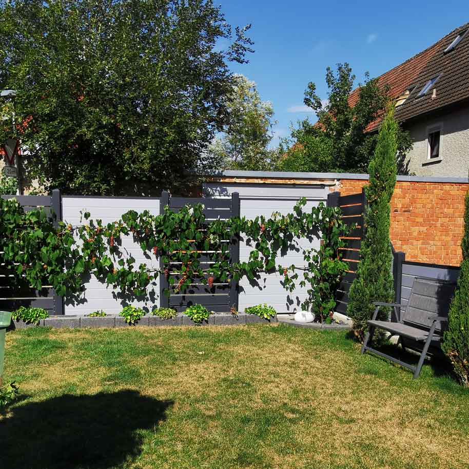 Sichtschutzzaun aus Kunststoff PVC in Grau und Anthrazit im Garten mit Blumenranken
