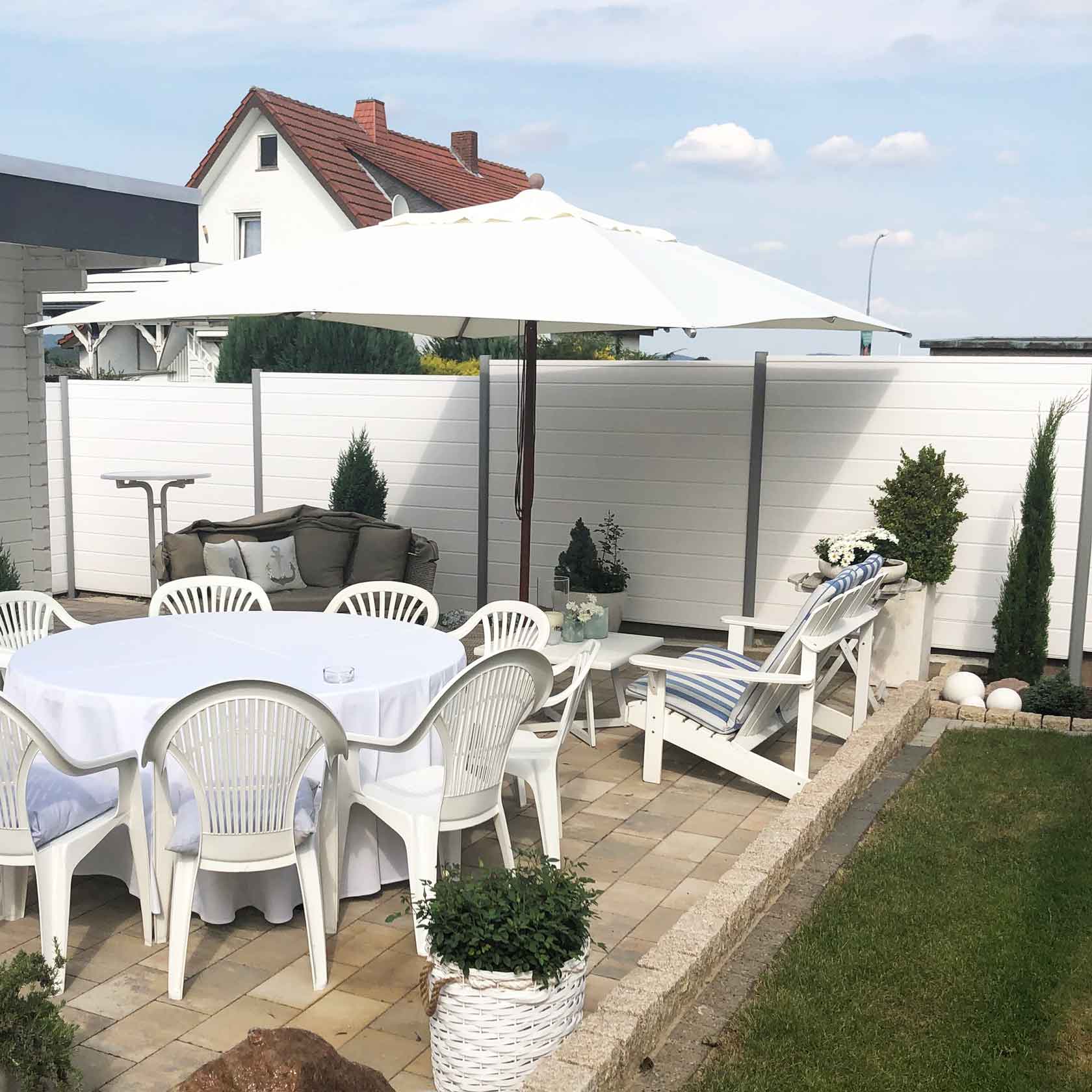 strahlende Sichtschutzwand in Weiss an einer sommerlichen Terrasse