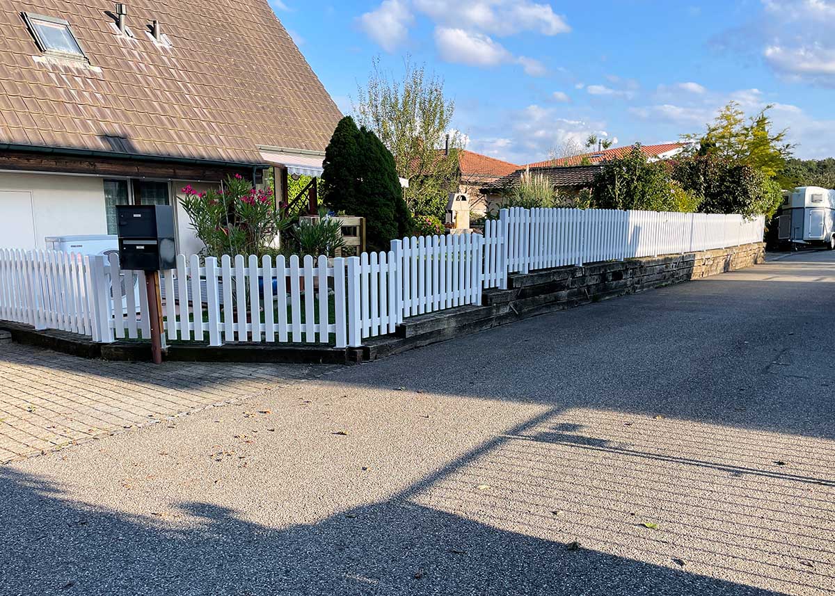 Weißer PVC-Zaun nach Maß: Klare Linie trotz Höhenunterschied