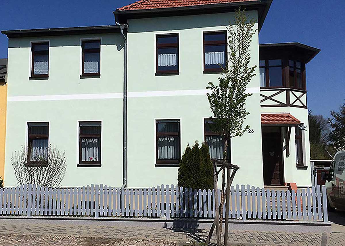 hellgrauer moderner Lattenzaun mit Unterbogen im Vorgarten, PVC-Zaun grau zum Aufdübeln, Kunststoffzaun in Silbergrau