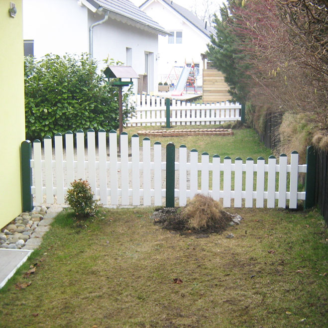 Lattenzaun in weiß und moosgrün als Wellenform im Hintergarten